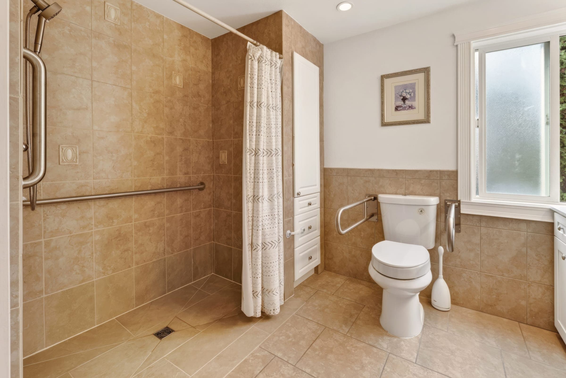 Bathroom with a curbless roll-in shower and grab bars beside the toilet