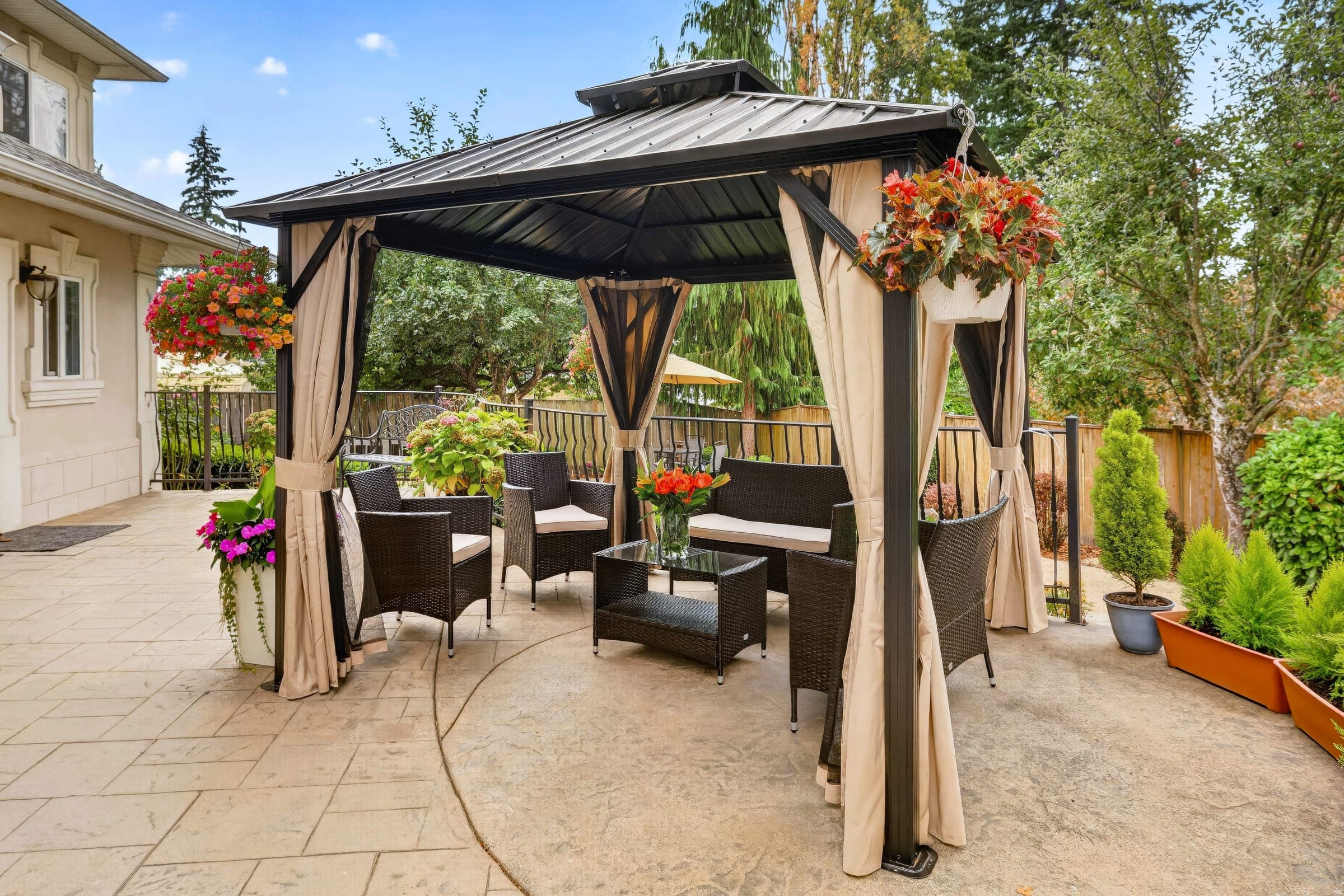 Covered gazebo seating on the patio beside the house
