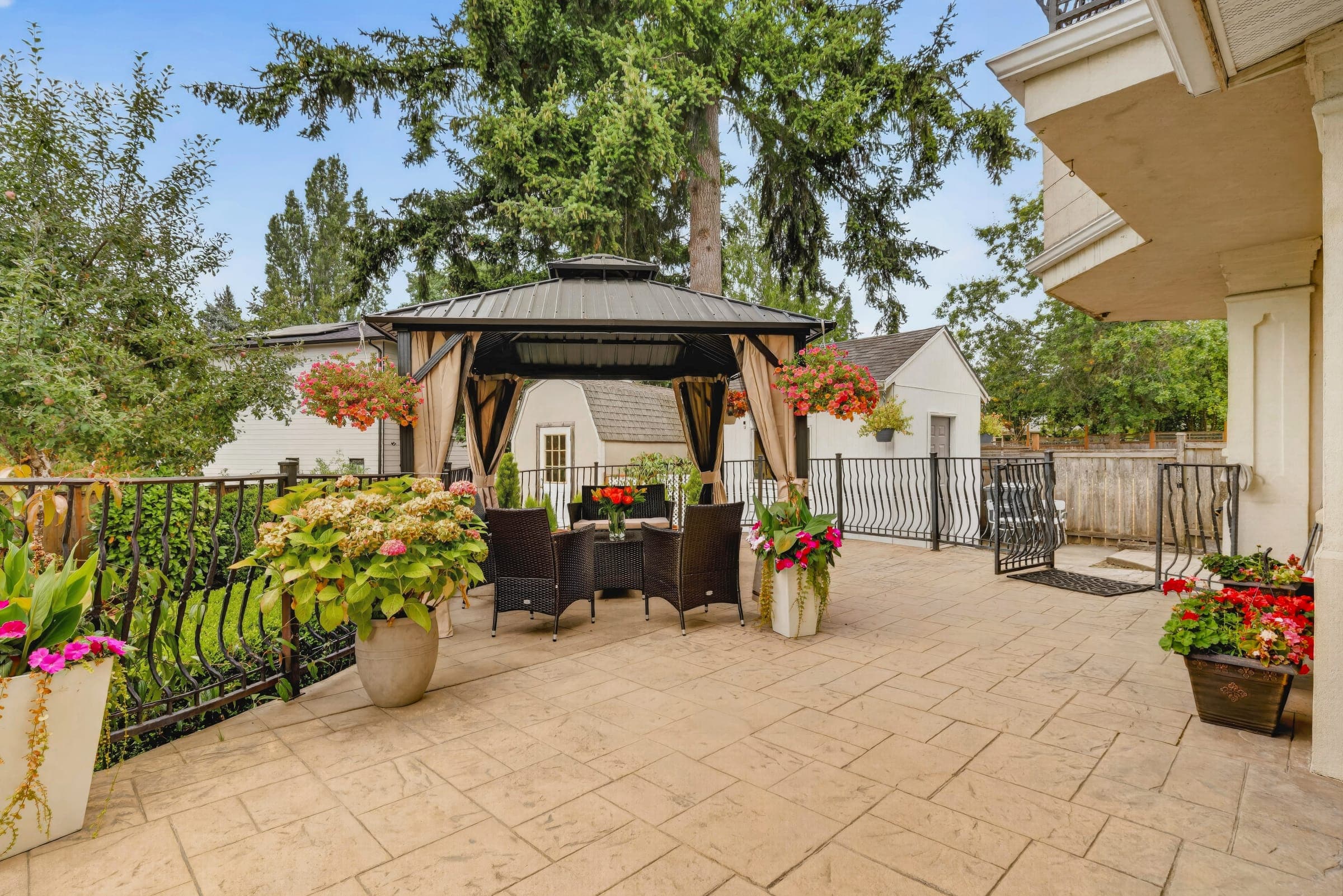 Back patio with a gazebo, hanging baskets, and potted flowers