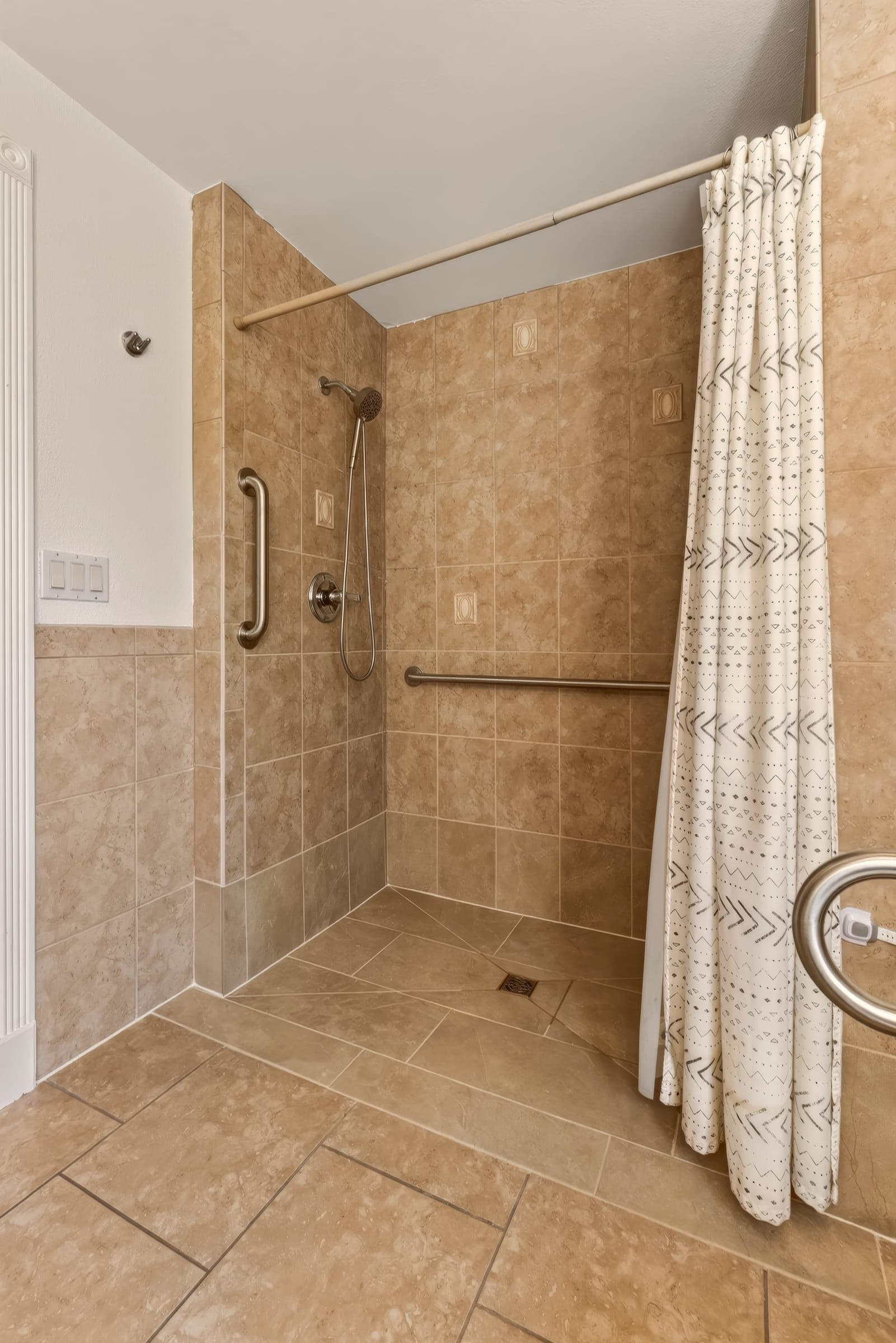 Curbless roll-in shower with grab bars and a handheld shower head